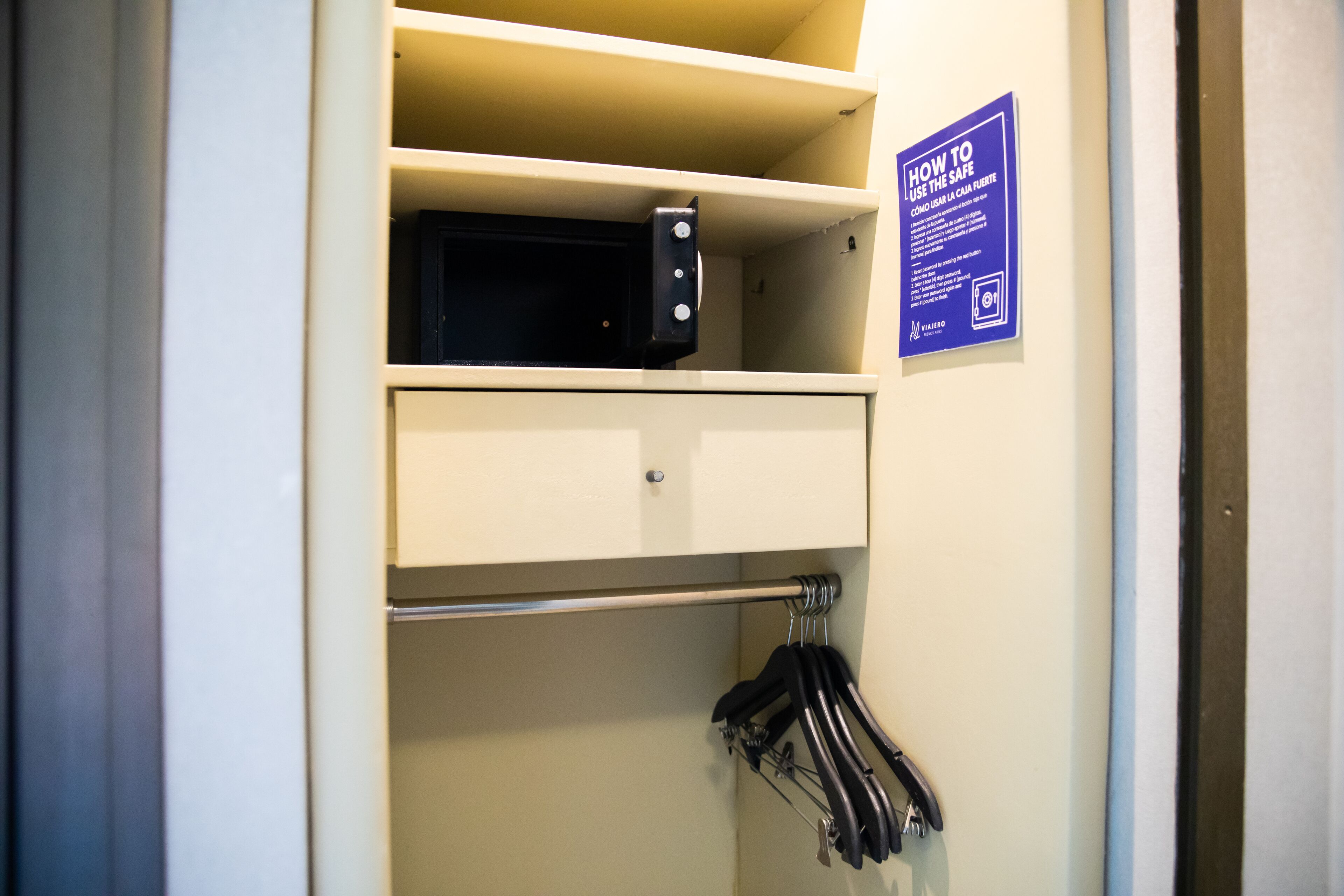 Une chambre d’hôtel équipée d’un four à micro-ondes posé sur une étagère, d’une affiche indiquant les consignes de sécurité et d’un porte-serviettes avec des serviettes.