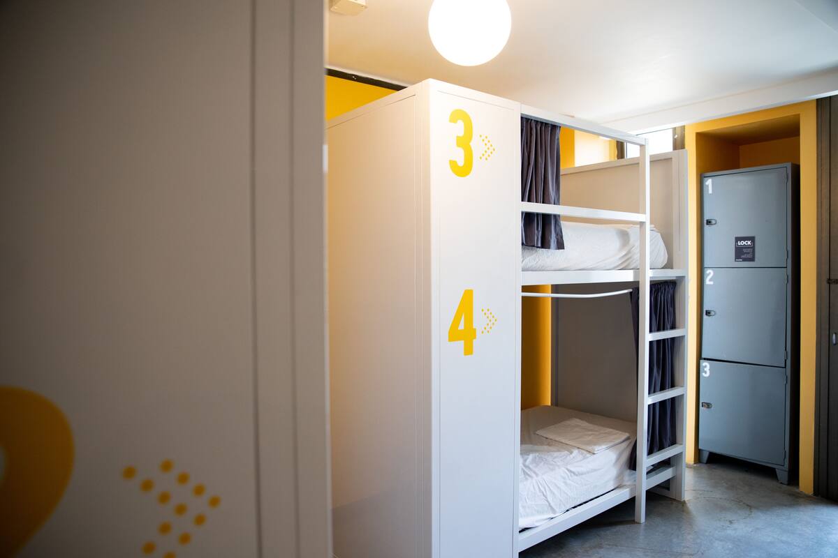 Una cama individual con los números 3 y 4, un armario de almacenamiento con los números 1, 2 y 3, y una puerta con cerradura.