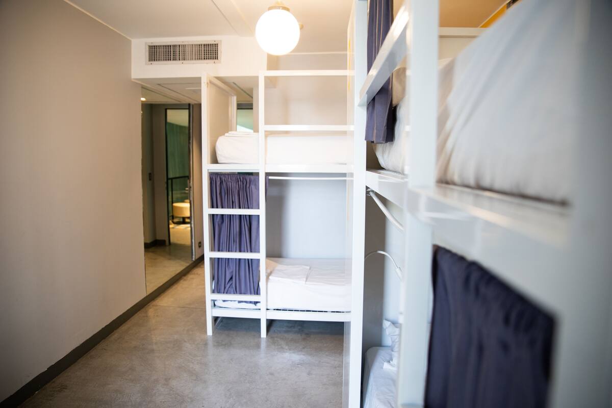 Habitación con literas, una escalera, armario y puerta que da a otra habitación.
