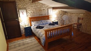 Ein Schlafzimmer mit einem hölzernen Bett, einem Nachttisch, einer Wanduhr und einem Ventilator.