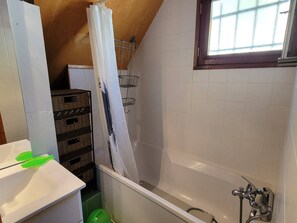 Ein Badezimmer mit Badewanne, Fenster und Duschvorhang.