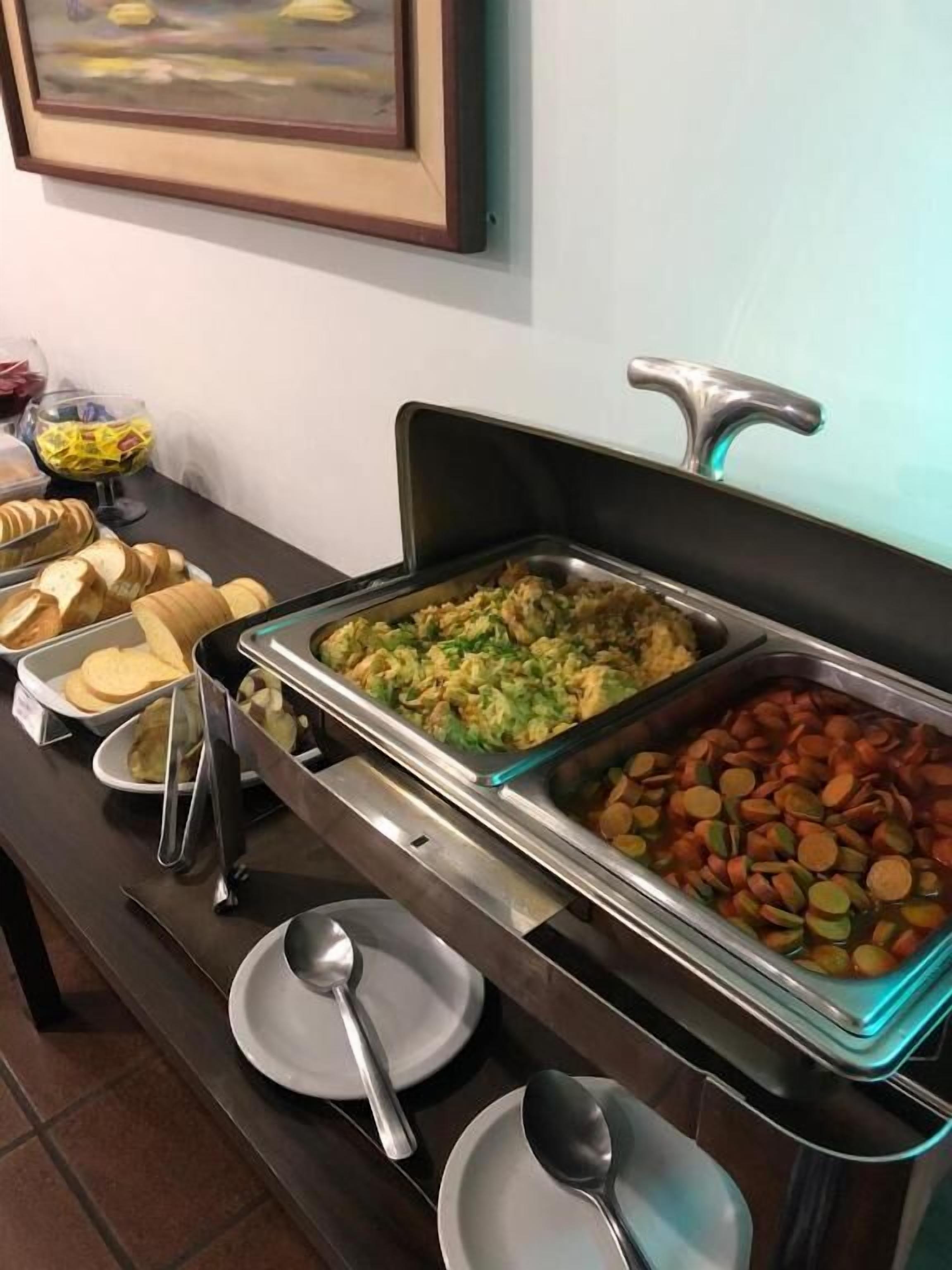 A buffet setup with various food items and utensils.