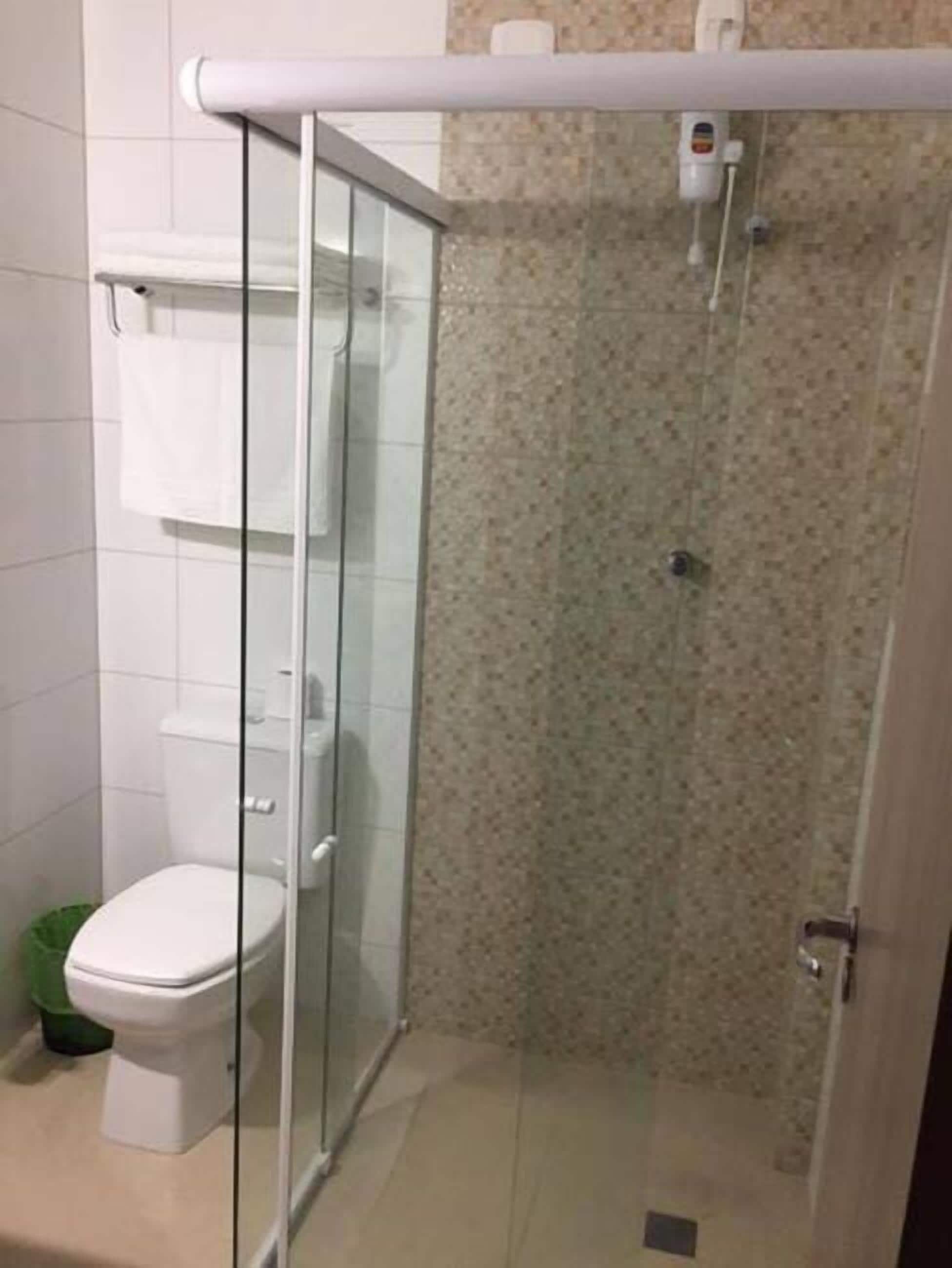 A modern bathroom with a glass-enclosed shower, a toilet, and a towel rack.
