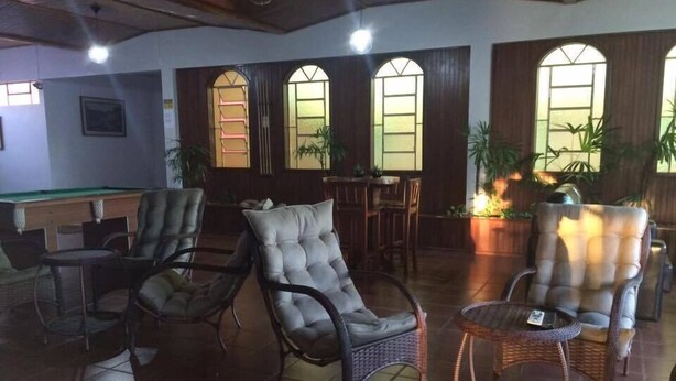 A lounge area with wicker furniture, a pool table, and large windows with arched tops.