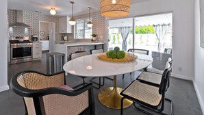 Una cocina moderna con comedor, que incluye una mesa redonda, sillas de mimbre y una lámpara colgante.