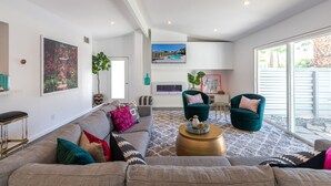 Amplia sala de estar con un sofá grande, dos sillones, una mesa de centro y un televisor montado en la pared.