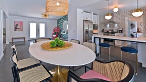 Una cocina moderna con armarios blancos, electrodomésticos de acero inoxidable y una isla central con taburetes.
