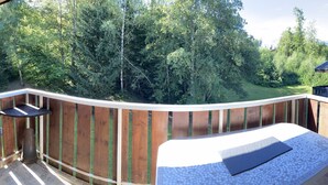 A balcony with a view of a forest and a mountain in the background.