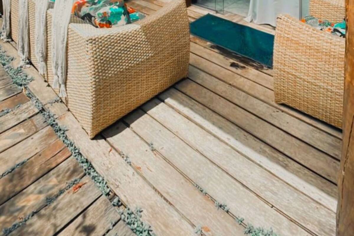 A wooden deck with wicker furniture and a glass door leading to a room.