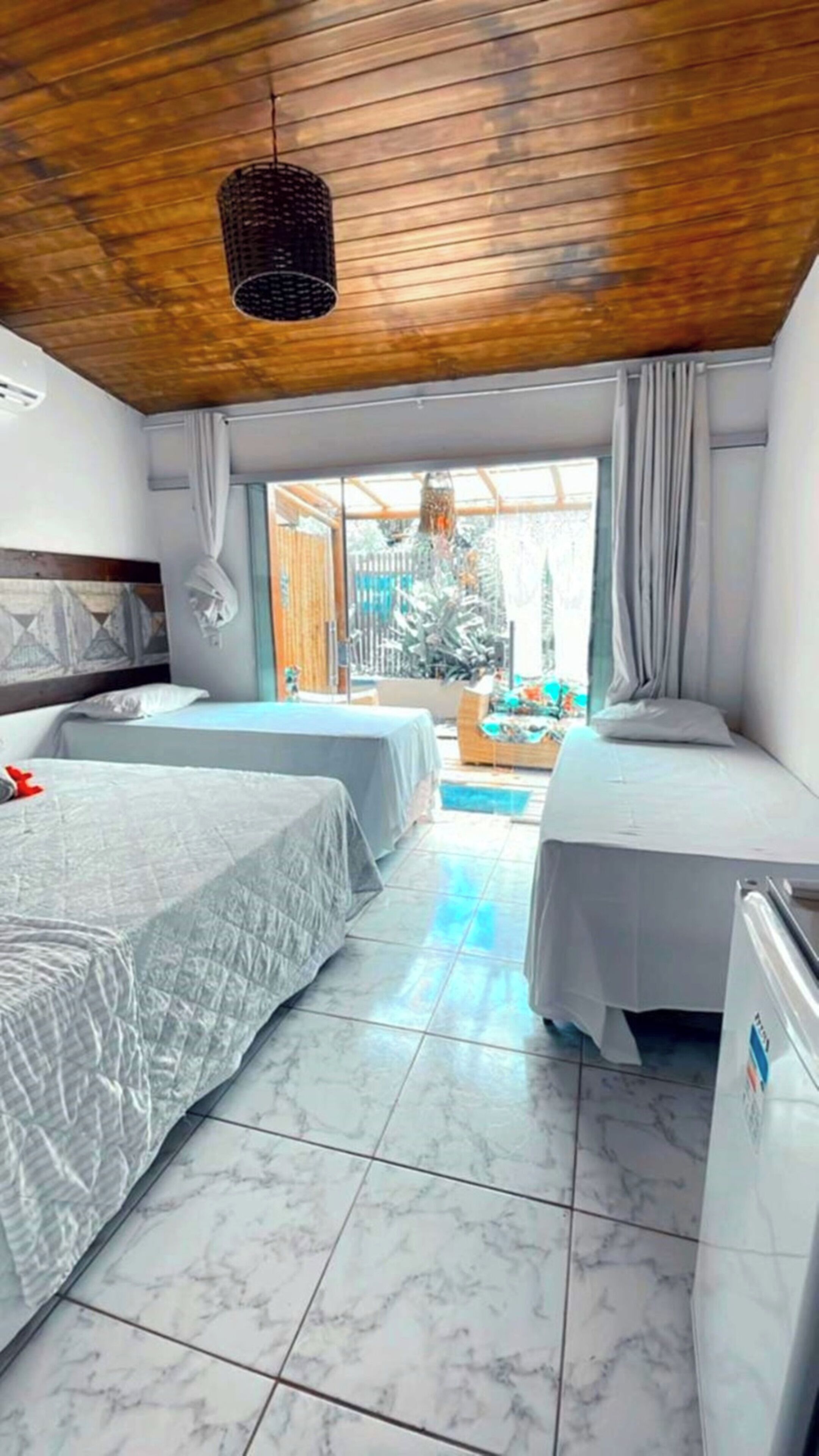 Ein Hotelzimmer mit zwei Betten, einer Holzbalkendecke, einem großen Fenster und Blick nach draußen.