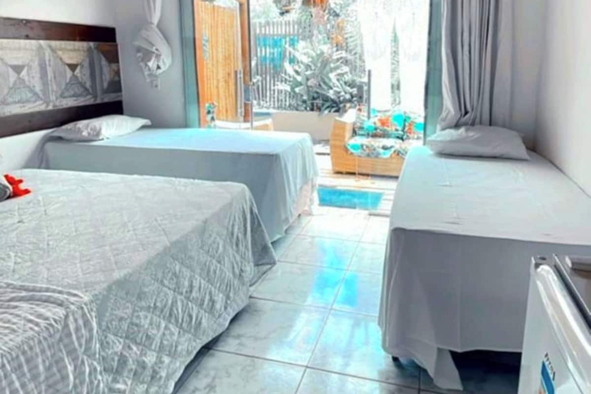 A hotel room with two beds, a wooden ceiling, a large window, and a view of the outside.