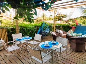 Eine Terrasss mit Korbmöbeln, Glastischen und Hängestühlen.