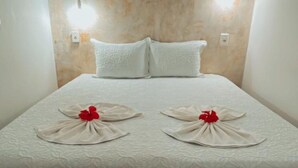 A hotel room with a bed, two pillows, and a headboard with wall-mounted lights. - Pousada Portal dos Golfinhos (Fernando de Noronha)