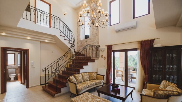 A spacious living area with a staircase, a chandelier, a dining area, and a view of the outdoors. - Private Heated pool★Close to the Beach★BBQ & Wifi (Galatas)