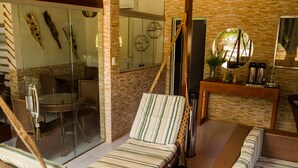 A room with a bed, a chair, a table, and a glass partition. - Pousada da Leide (Fernando de Noronha)