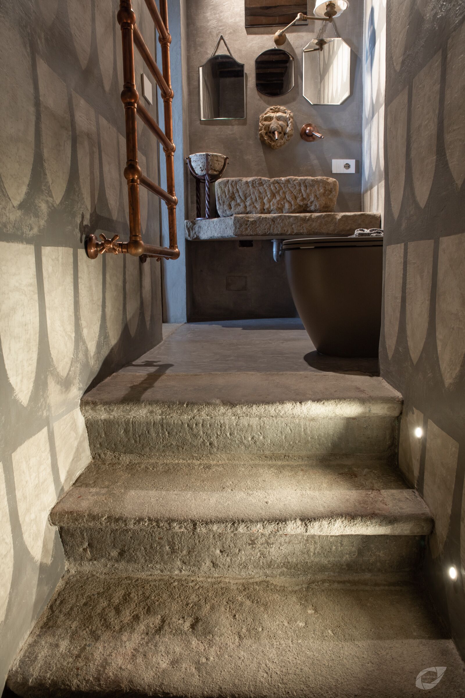 Eine enge Treppe führt zu einem Badezimmer mit einer Badewanne, einem Waschbecken und einem Spiegel.