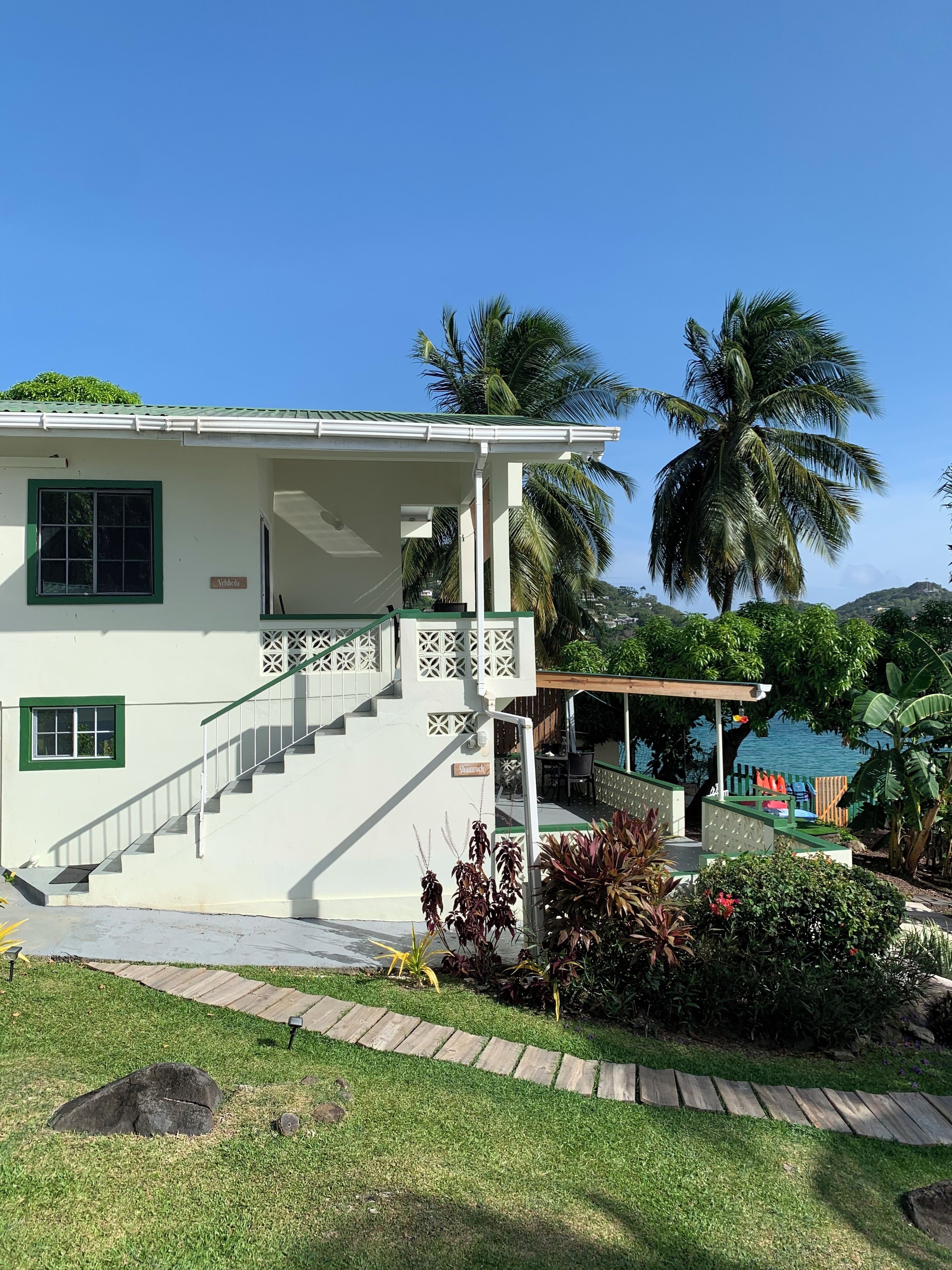A two-story building with a covered porch, a staircase, and a view of the sea.
