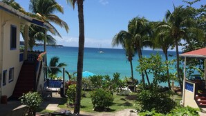 A tropical resort with a view of the ocean, palm trees, and a staircase leading to a building. - Hideaway Apartments Grenada (St. George's)