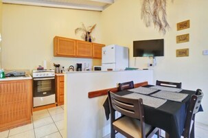 Una cocina compacta con armarios de madera, un refrigerador y un comedor con mesa y sillas.