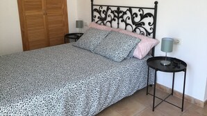 Une chambre à coucher avec un lit, une table de chevet, une lampe et une armoire en bois.