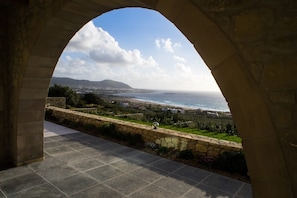 A stone archway overlooking a coastal landscape with a view of the sea and distant hills.