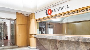A reception area with a marble counter, a wooden door, and a glass wall. - Capital O Andrade, Mexico City (Mexico City)