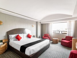 Une chambre d’hôtel avec un grand lit, un bureau, une chaise et une vue sur la ville.