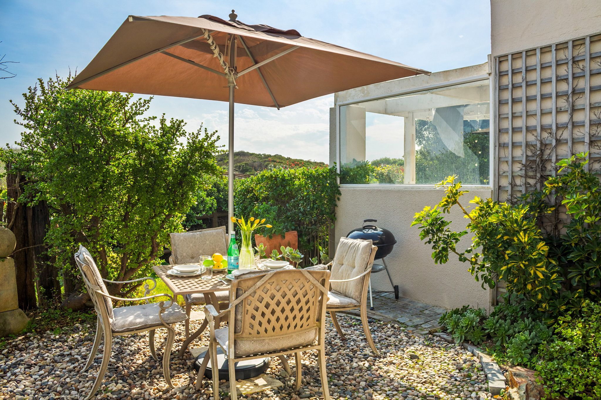Une terrasse extérieure avec des meubles en osier, une table et un parasol.
