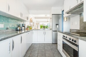 A modern kitchen with white cabinets, a stainless steel stove, and a view of the outdoors.