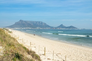 A beach with a sandy shore, a wooden fence, and a mountain in the background.