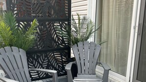 Un patio con dos sillas Adirondack y una mesita.