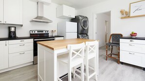 Una cocina moderna con armarios blancos, una isla de madera y una lavadora blanco y negro.