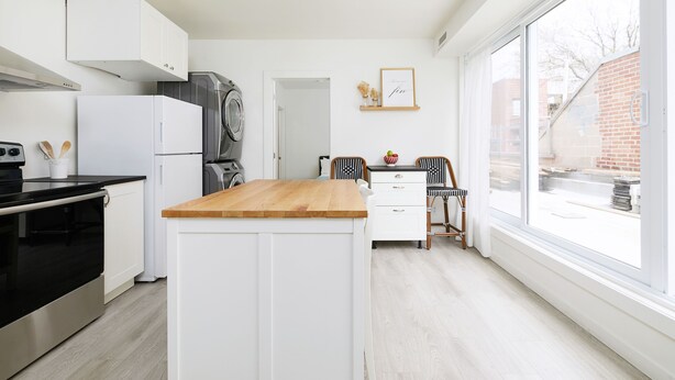 Una cocina moderna con armarios blancos, encimera de madera y un amplio ventanal con vistas al exterior.