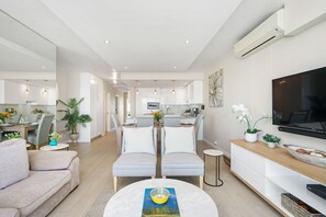A modern living room with a sofa, a coffee table, and a TV on a wooden console. - Dolphin Beach H106 (Cape Town)
