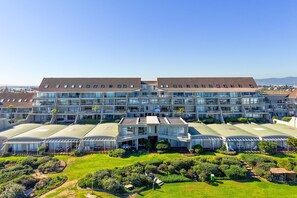 A modern hotel with multiple floors, large glass windows, and a well-maintained garden. - Dolphin Beach H106 (Cape Town)