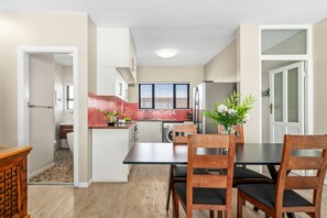 A modern kitchen with white cabinets, a red backsplash, and a dining area with a table and chairs.