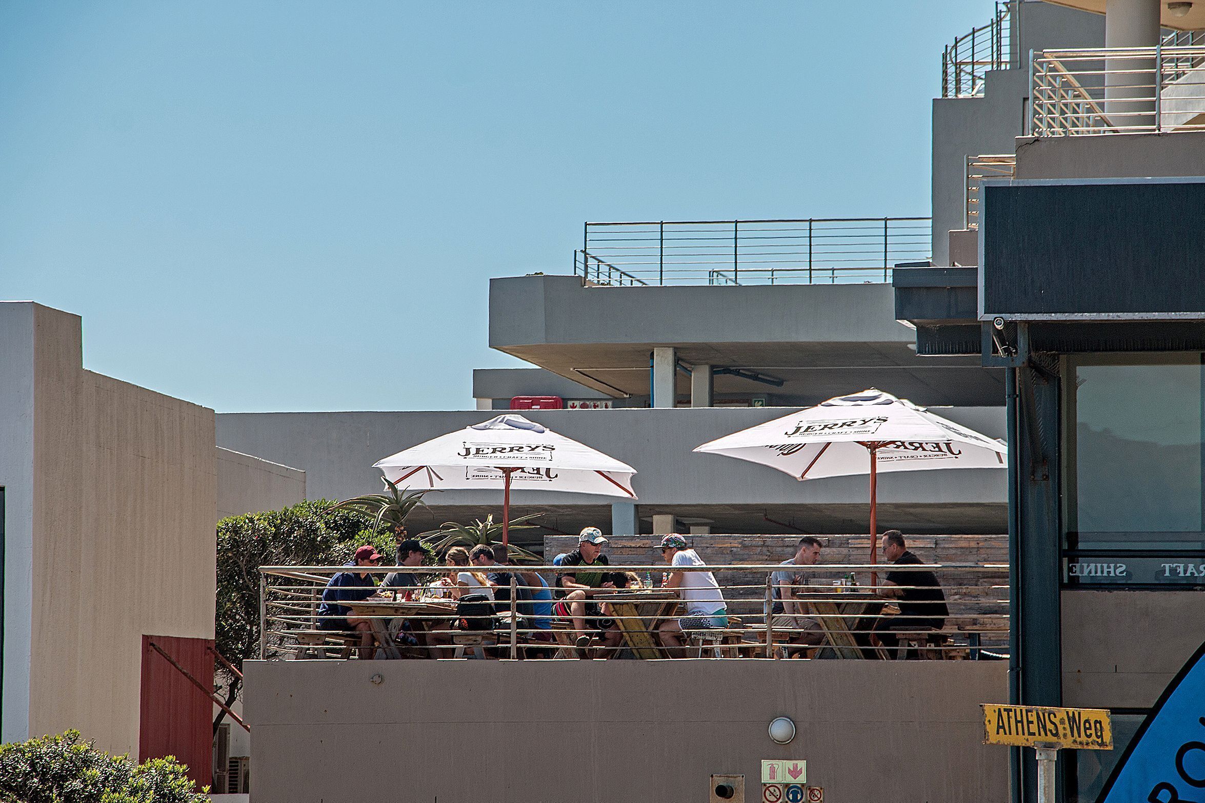A rooftop bar with outdoor seating, umbrellas, and a view of the city skyline.