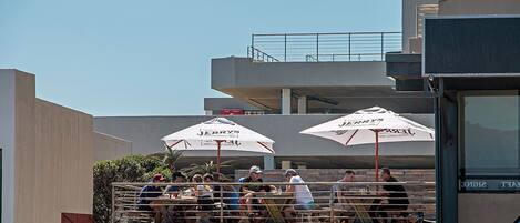 A rooftop bar with outdoor seating, umbrellas, and a view of the city skyline.