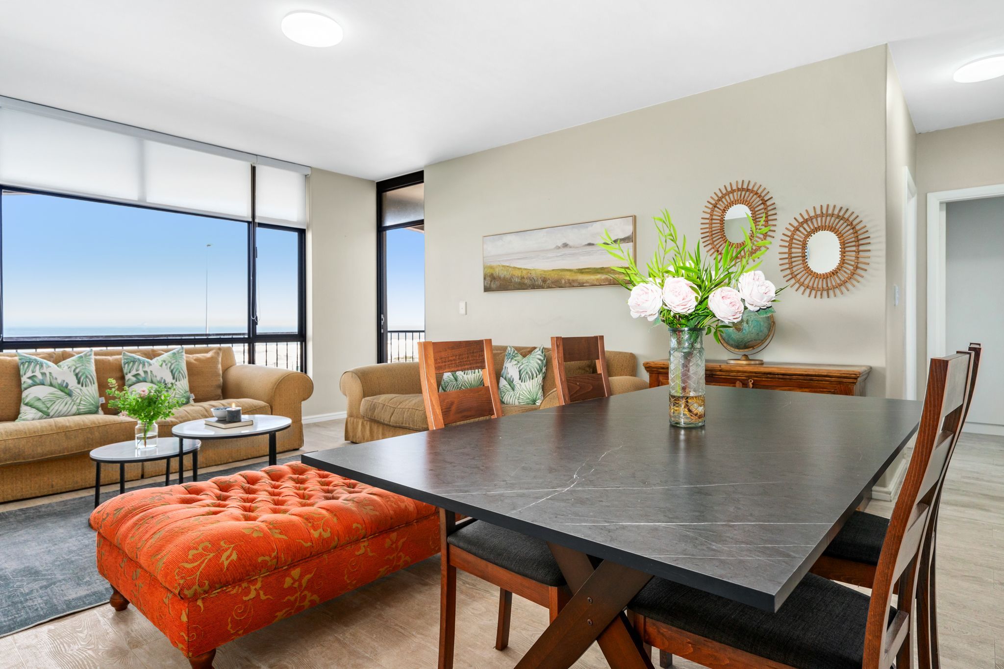 Una sala de estar moderna con una gran mesa de comedor, asientos cómodos y vistas al exterior.