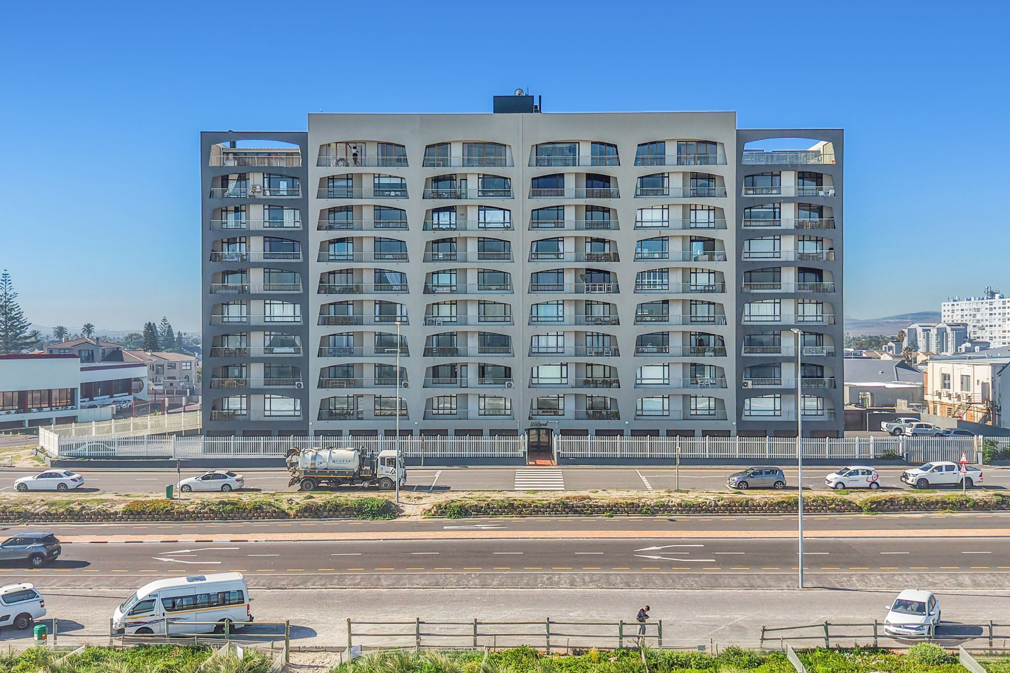 A multi-story building with a modern architectural design, featuring balconies and large windows.