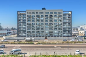 A multi-story building with a modern architectural design, featuring balconies and large windows.