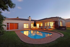 A residential property with a swimming pool, a covered patio, and a well-maintained lawn. - Durham Close 31 (Cape Town)