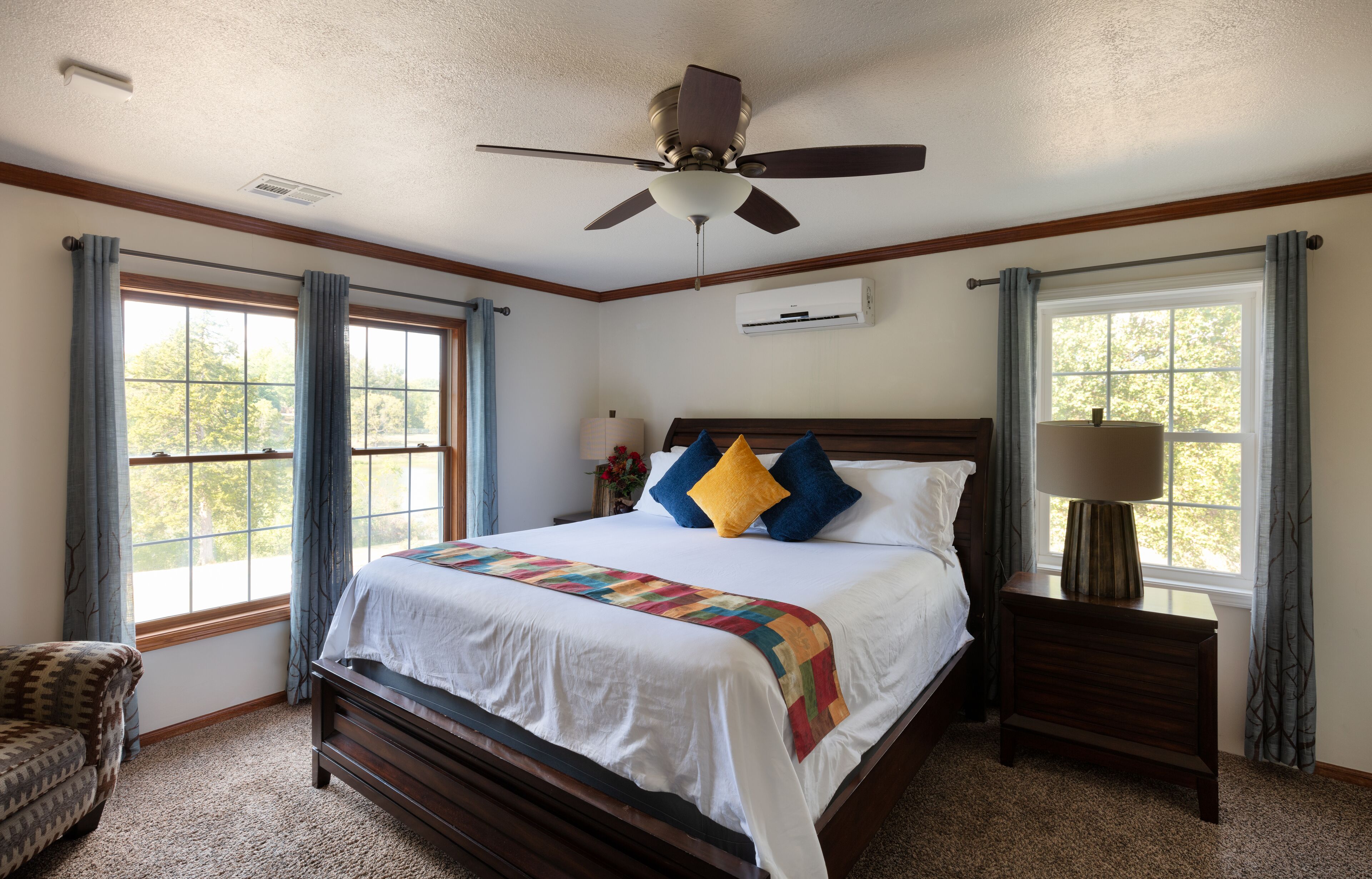 A bedroom with a bed, a nightstand, a chair, and a ceiling fan.