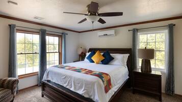 A bedroom with a bed, a nightstand, a chair, and a ceiling fan.