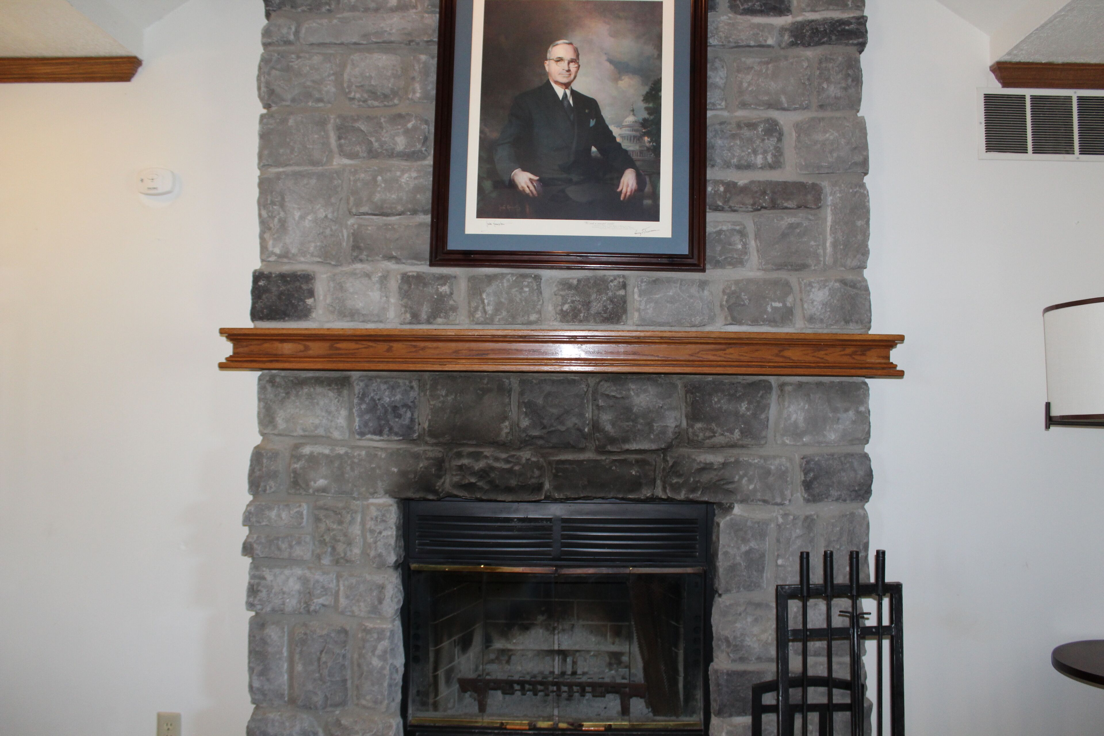 A stone fireplace with a framed portrait above it.