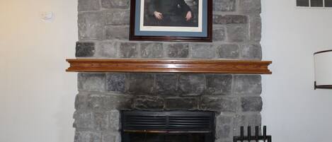 A stone fireplace with a framed portrait above it.