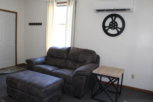 A living room with a leather sofa, a matching ottoman, and a small wooden table. - Basswood Resort (Platte City)