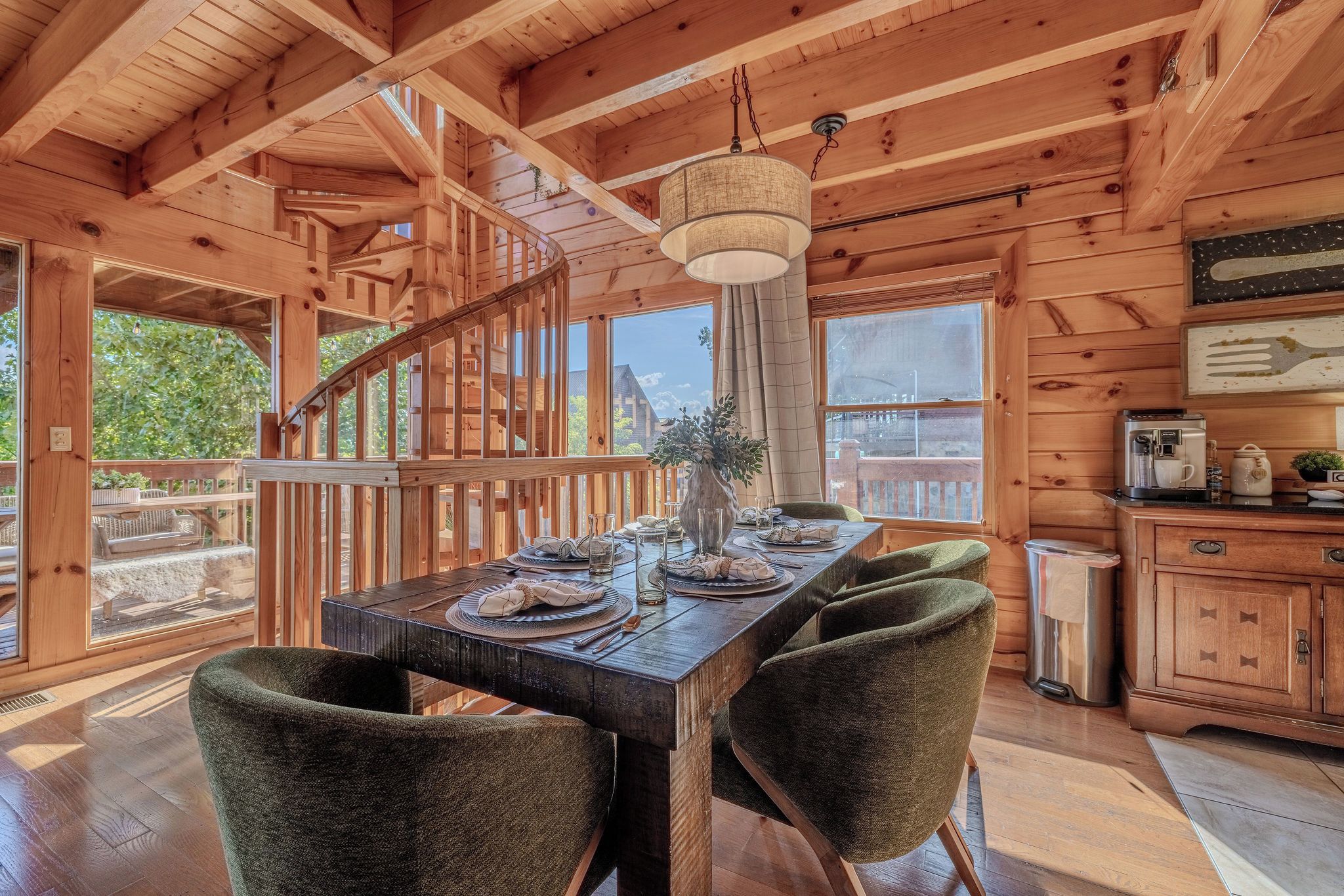 A wooden interior with a dining table set for four, a staircase, and a kitchen area.