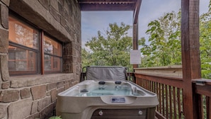 Un jacuzzi con controles, una terraza de madera, paredes de piedra y una ventana.