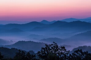 Eine gebirgige Landschaft mit terrassenförmigen Hügeln und einem bewaldeten Vordergrund.